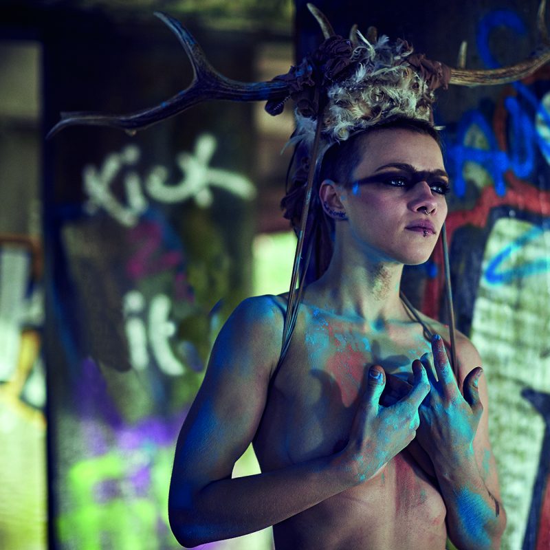 woman in body paint wearing a stag horn headdress
