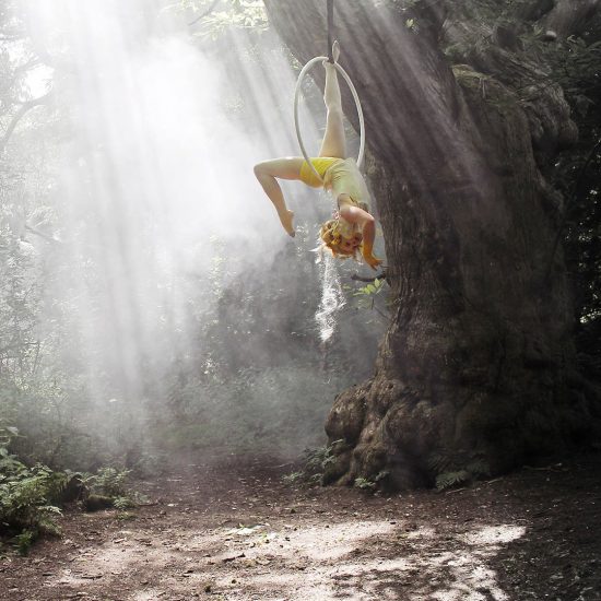 Kate George hanging from a trapeze in the forest